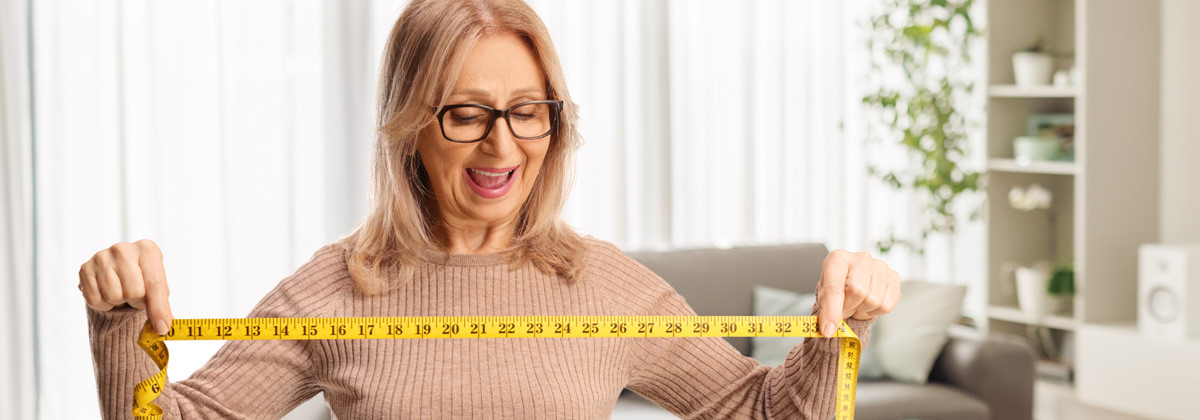 Kobieta uśmiecha się i trzyma miarę krawiecką